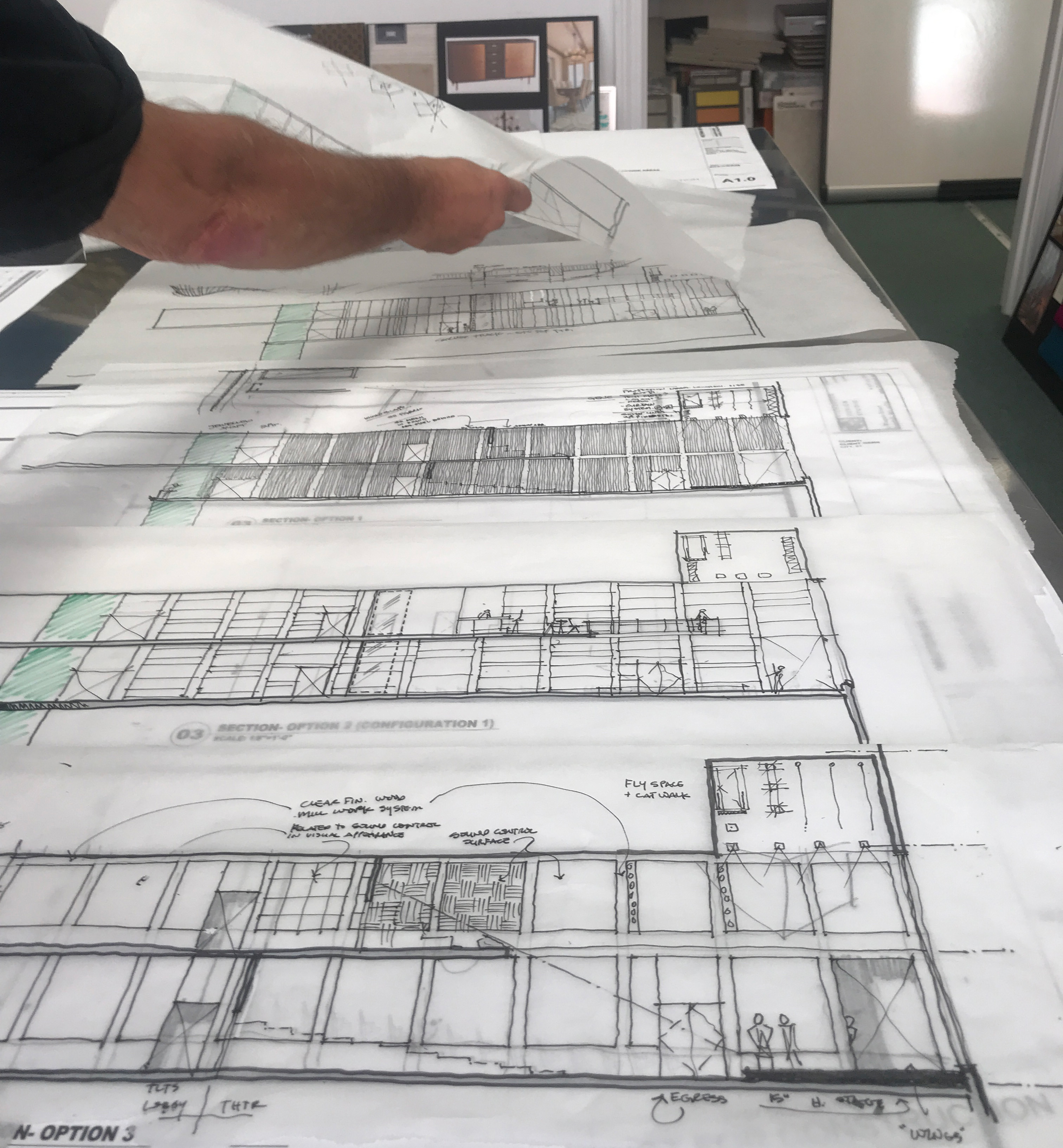 A hand laying out blueprints